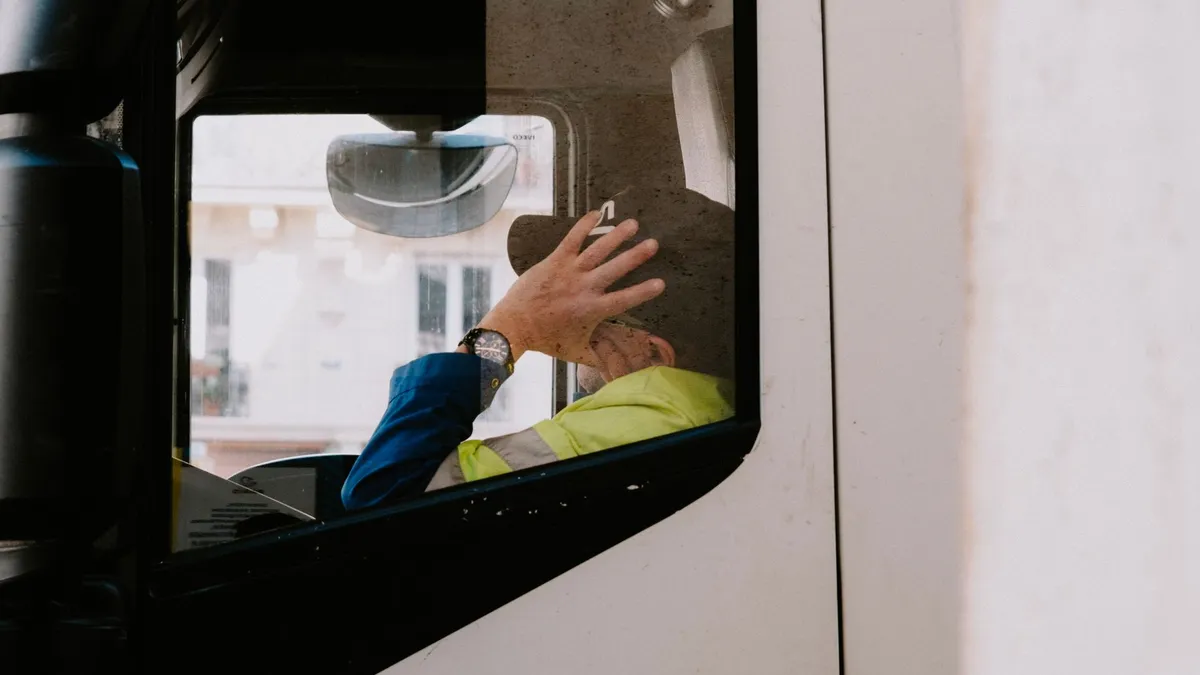 Conductor de camión esperando en la cabina durante una parada de carga o descarga en el muelle